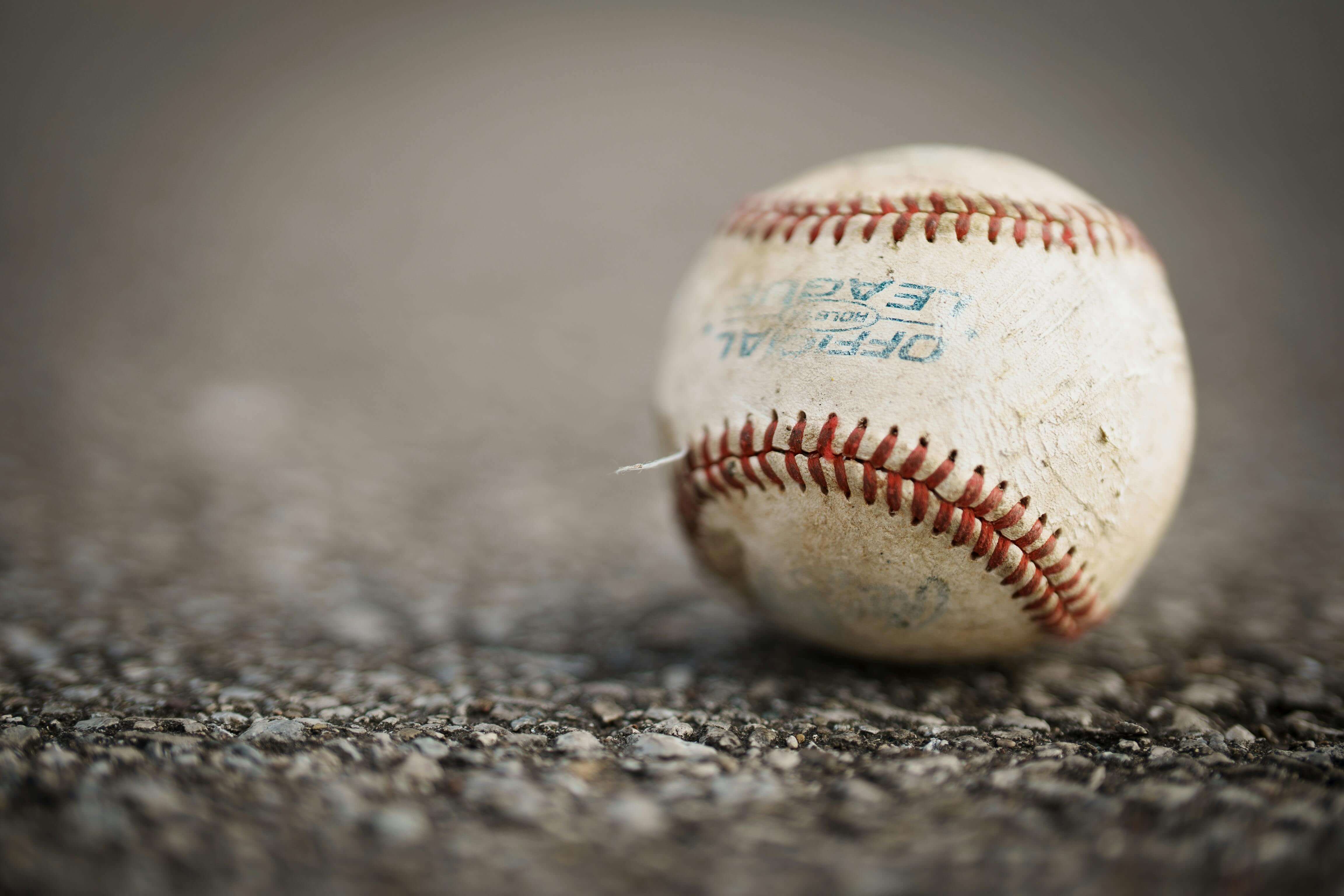 A baseball sitting on a field of dirt.